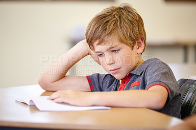 Buy stock photo Class, book and bored child at desk, learning and education with school exam. Reading notebook, studying for test and boy student in classroom with knowledge and thinking with depression on project.