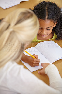 Buy stock photo Teacher helping student in classroom, education and writing in notebook with pencil, teaching and learning for development. Scholarship, academic study and young girl and woman in lesson at school