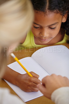 Buy stock photo Closeup of teacher helping student, education and writing in notebook, teaching and learning for development. People in classroom to learn, academic study and young girl, woman in lesson at school