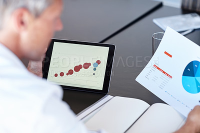 Buy stock photo Cropped shot of a businessman looking at graphs on a digital tablet in an office