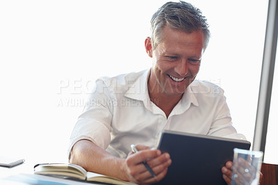 Buy stock photo Shot of a handsome businessman using a digital tablet in the office