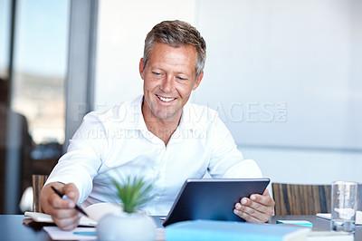 Buy stock photo Shot of a handsome businessman using a digital tablet in the office