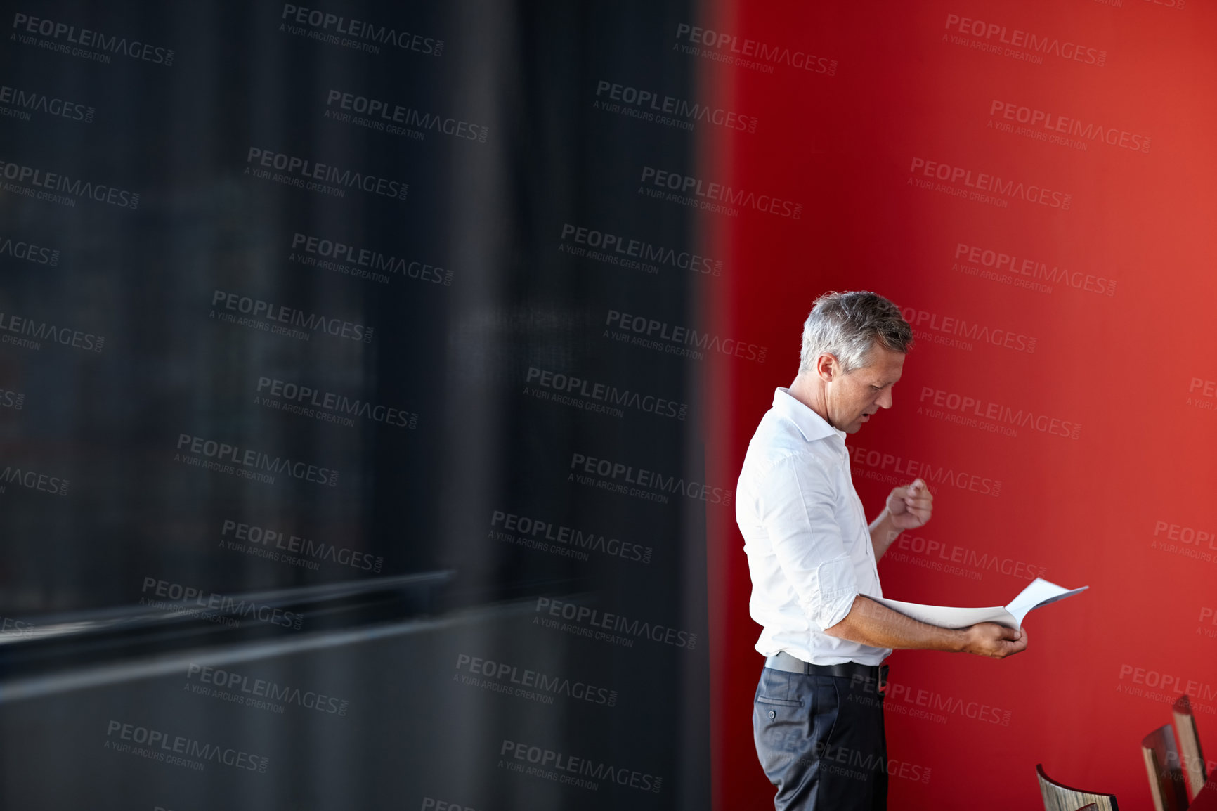 Buy stock photo Shot of a handsome businessman going through his paperwork in the office