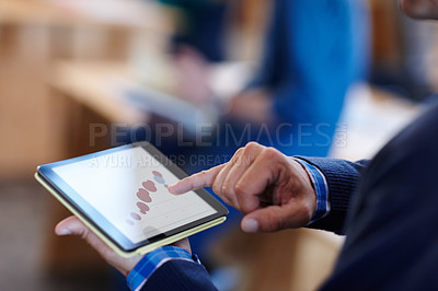 Buy stock photo Cropped shot of a man looking at graphs on a digital tablet in an office