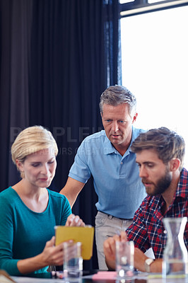 Buy stock photo Shot of a group of colleagues having a discussion over a digital tablet