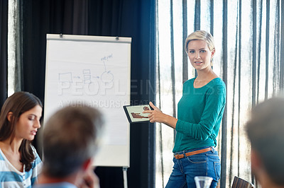 Buy stock photo Shot of an attractive woman showing her colleagues graphs on a digital tablet during her presentation