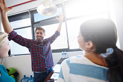 Buy stock photo Shot of a man raising his arms in victory with two female colleagues in the foreground