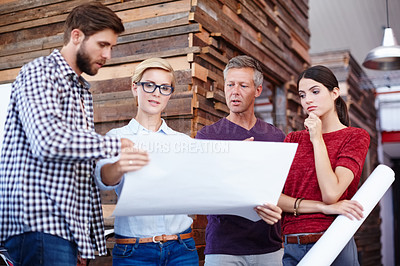 Buy stock photo A group of colleagues looking over some plans