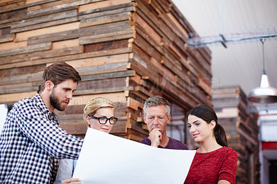 Buy stock photo A group of colleagues looking over some plans