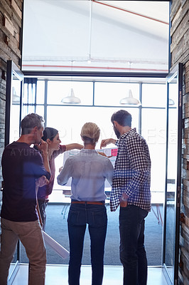 Buy stock photo A group of colleagues looking over some plans