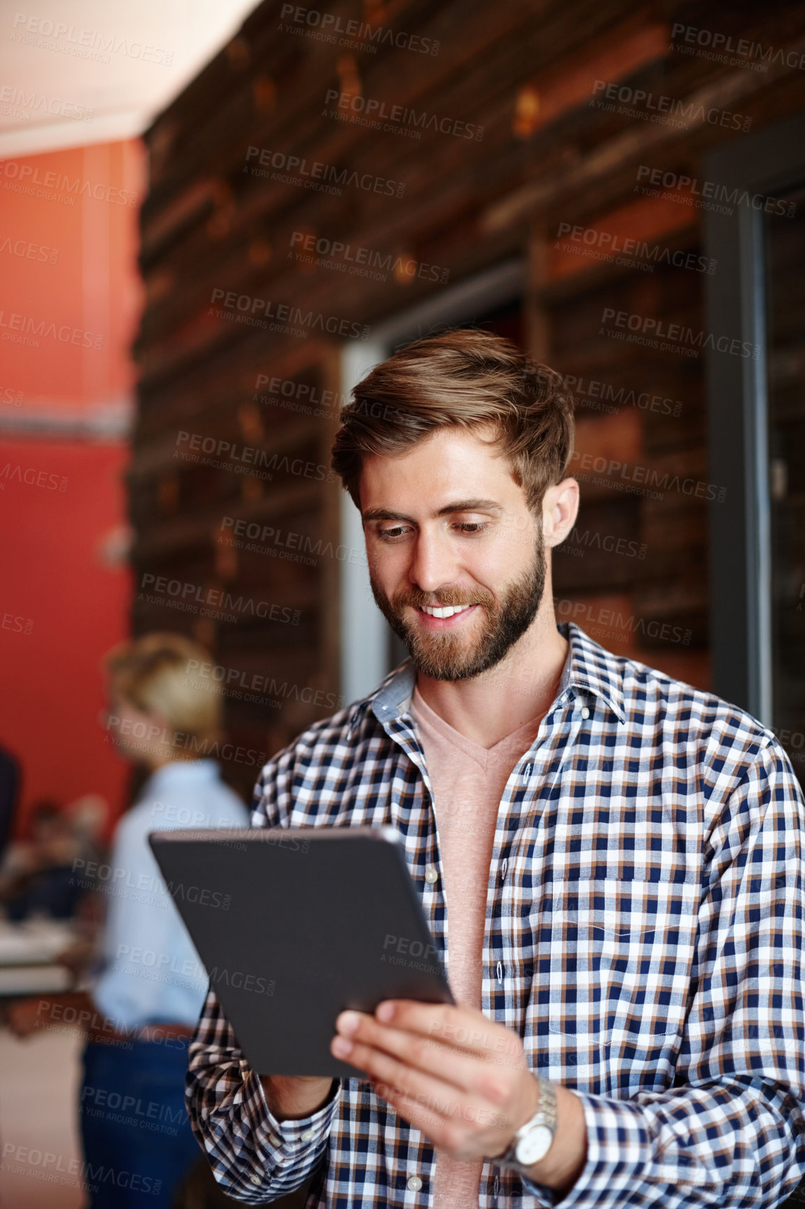 Buy stock photo Shot of a young designer using a tablet with her colleagues standing in the background