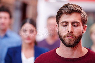 Buy stock photo Shot of an office worker standing with his eyes closed with coworkers in the background