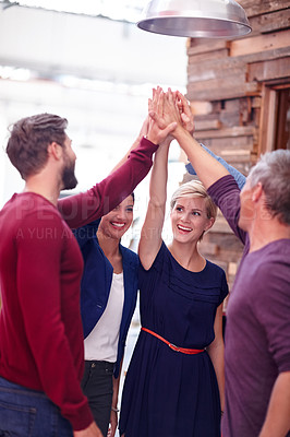 Buy stock photo A group of creative professionals high-fiving each other to celebrate a success