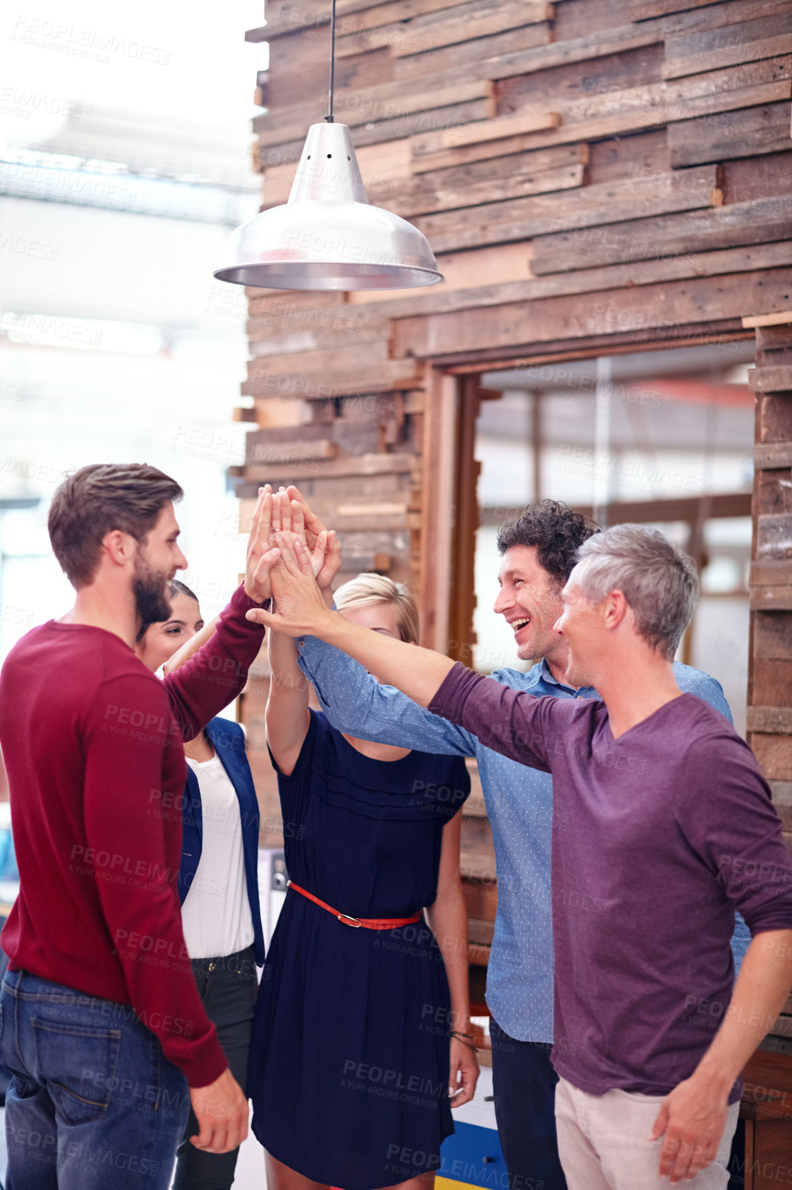 Buy stock photo A group of creative professionals high-fiving each other to celebrate a success