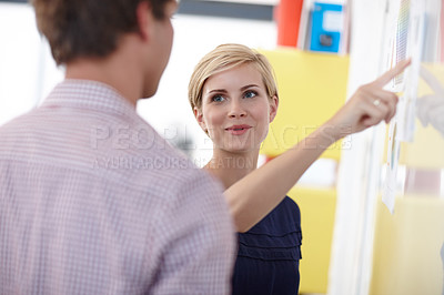Buy stock photo Cropped shot of a young businesswoman explaining something to her colleague at a whiteboard