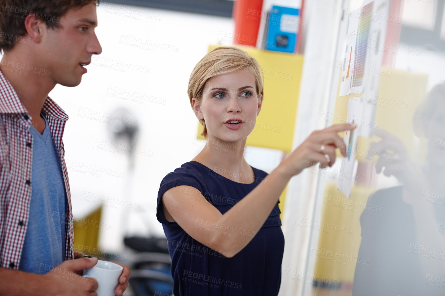Buy stock photo Cropped shot of a young businesswoman explaining something to her colleague at a whiteboard