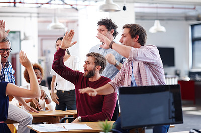 Buy stock photo A group of excited designers celebrating a success during an informal office meeting