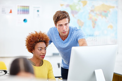 Buy stock photo Cropped shot of two young colleagues working on a computer