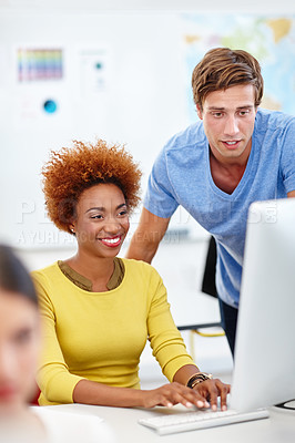 Buy stock photo Cropped shot of two young colleagues working on a computer