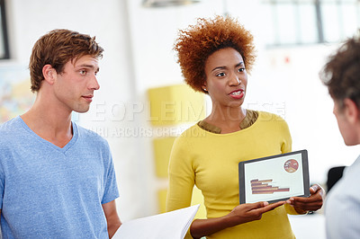 Buy stock photo Cropped shot of an attractive young businesswoman showing a colleagues something on her tablet