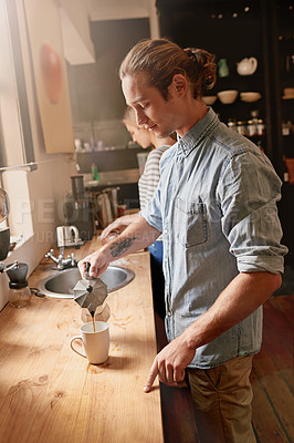 Buy stock photo Cropped shot of a handsome young man pouring a warn beverage