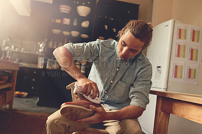 Buy stock photo Cropped shot of a handsome young man cleaning his shoes in the kitchen