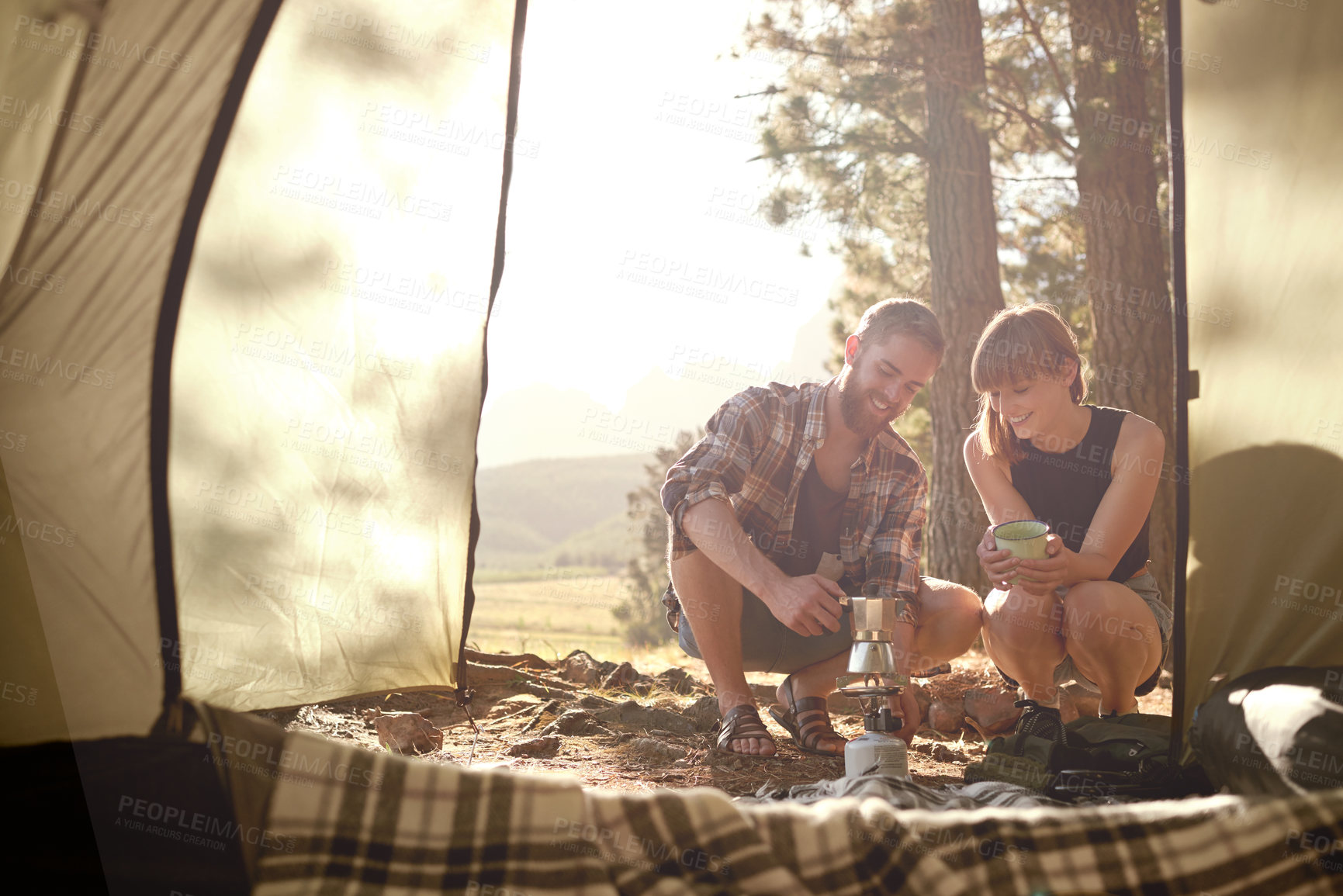 Buy stock photo Shot of a young couple making coffee on a camp stove while camping