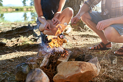 Buy stock photo Cropped shot of two campers roasting marshmallows over a campfire