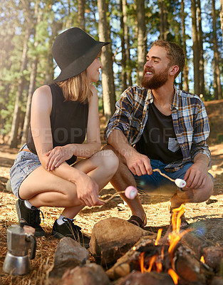 Buy stock photo Shot of two campers roasting marshmallows over a campfire