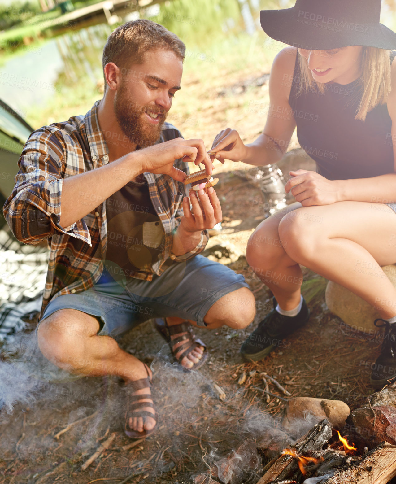 Buy stock photo Shot of a young couple making smores while camping