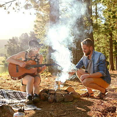 Buy stock photo Shot of a young woman playing guitar for her boyfriend at their campsite