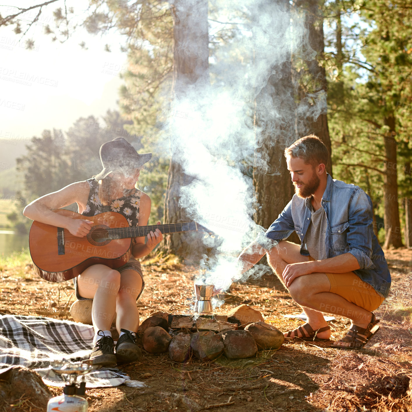 Buy stock photo Shot of a young woman playing guitar for her boyfriend at their campsite