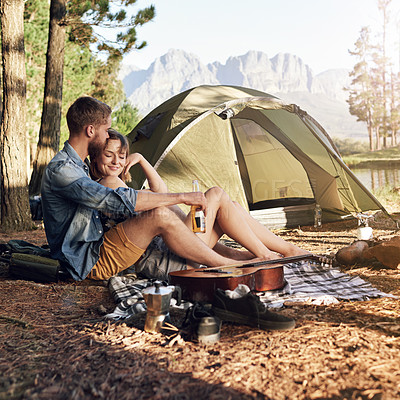 Buy stock photo Shot of an affectionate young couple sitting at their campsite