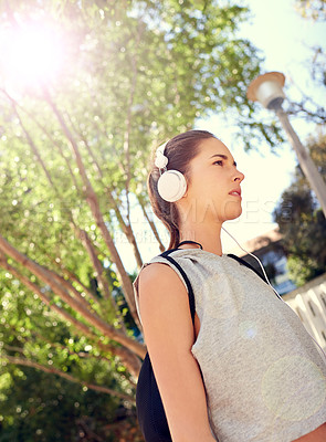 Buy stock photo Shot of a sporty young woman listening to music on her way to the gym