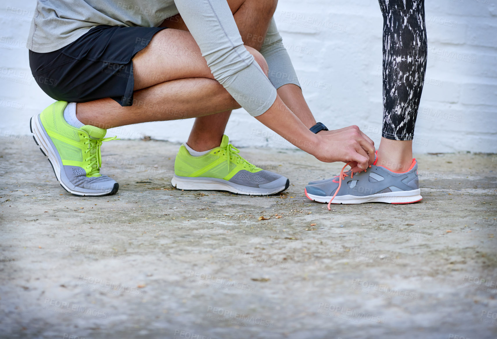 Buy stock photo Shot of a young man tying his girlfriend's shoelaces before a workout
