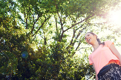 Buy stock photo Shot of a sporty young woman walking beside trees