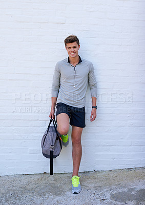 Buy stock photo Shot of a handsome young man holding his gym bag, ready for a workout