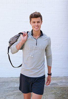 Buy stock photo Shot of a handsome young man holding his gym bag, ready for a workout
