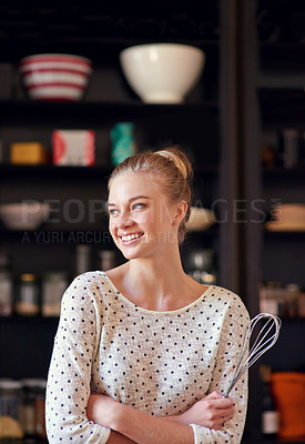 Buy stock photo Shot of a young woman standing with a whisk in her kicthen