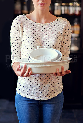 Buy stock photo Cropped shot of a young woman standing in her kitchen holding baking dishes