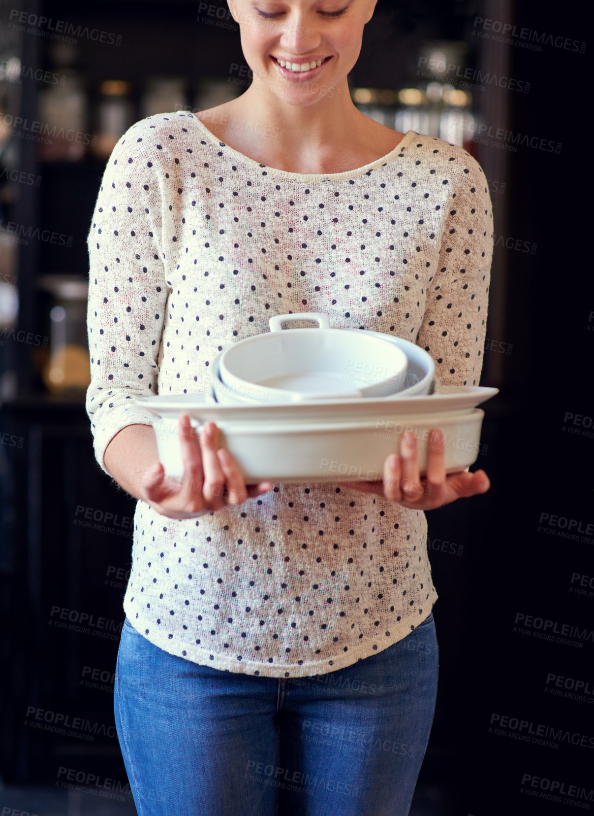 Buy stock photo Cropped shot of a young woman standing in her kitchen holding baking dishes