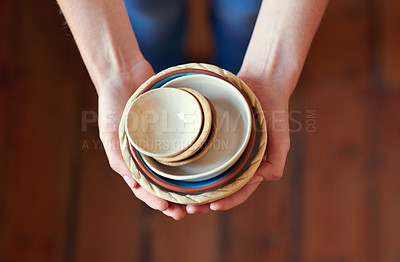 Buy stock photo Cropped shot of a young woman holding a stack of ceramic bowls in her kitchen