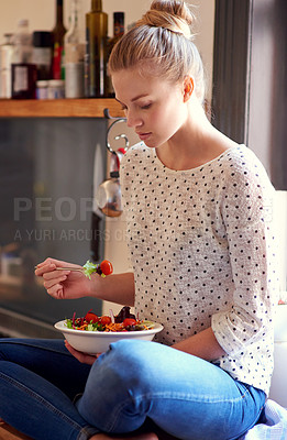 Buy stock photo Shot of a young woman eating a healthy salad in her kitchen