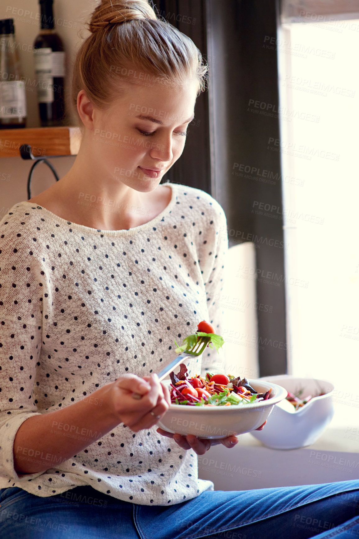 Buy stock photo Shot of a young woman eating a healthy salad in her kitchen