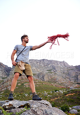 Buy stock photo Full length shot of a handsome young man throwing a rope while hiking