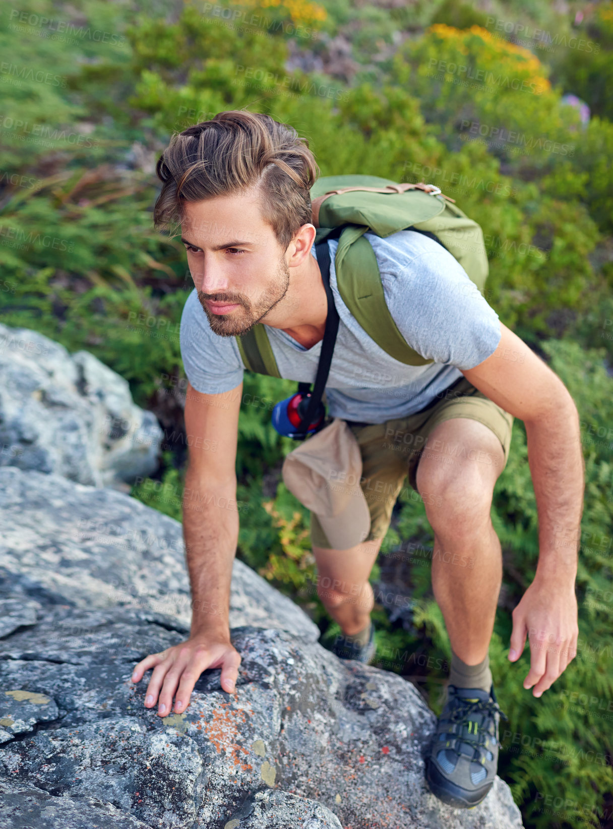 Buy stock photo Shot of a handsome young man scaling a mountain