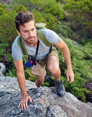 Buy stock photo Shot of a handsome young man scaling a mountain