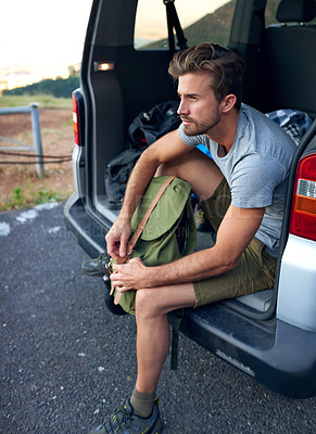 Buy stock photo Cropped shot of a man sitting in the back of his vehicle with a backpack