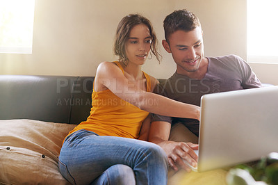 Buy stock photo Shot of a happy young couple using a laptop together on the sofa at home