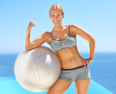 Buy stock photo Portrait of an attractive young woman flexing her bicep on an exercise ball
